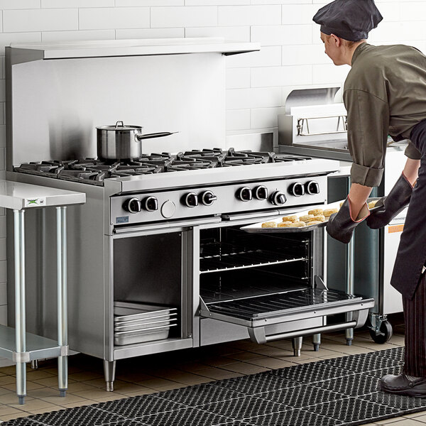 A man in a chef's hat using a Garland 8 burner range to cook food.