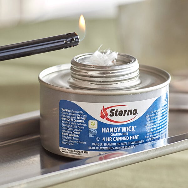 A lit Sterno Handy Wick canister on a table.