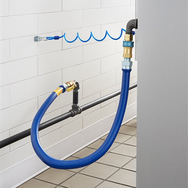 A blue Dormont gas connector hose connected to a white wall.