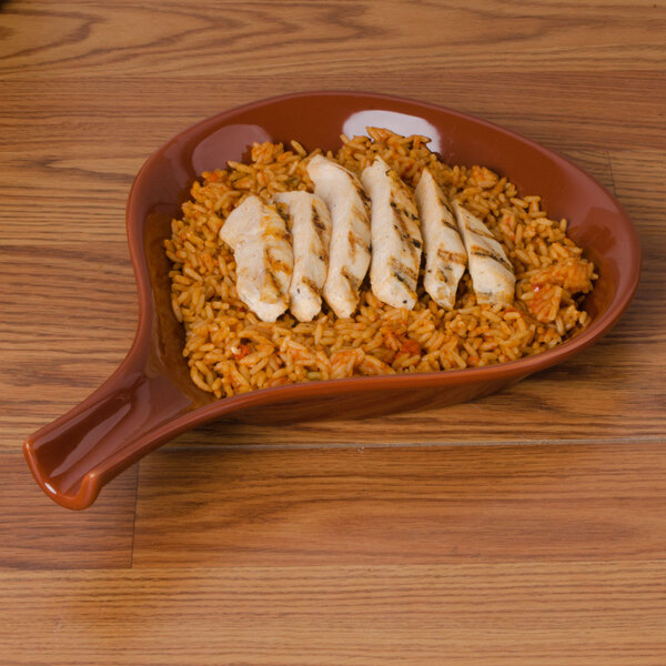 A CAC brown fry pan plate with chicken and rice on it.