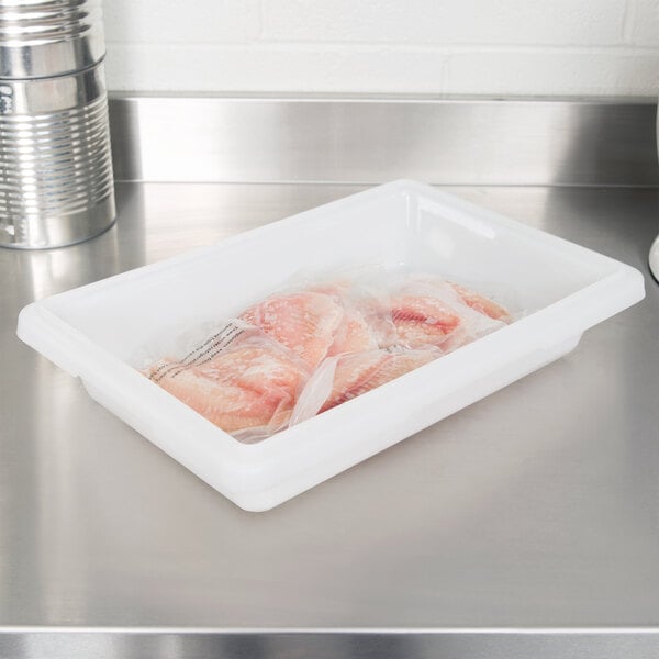 A white Cambro food storage box filled with raw chicken meat.
