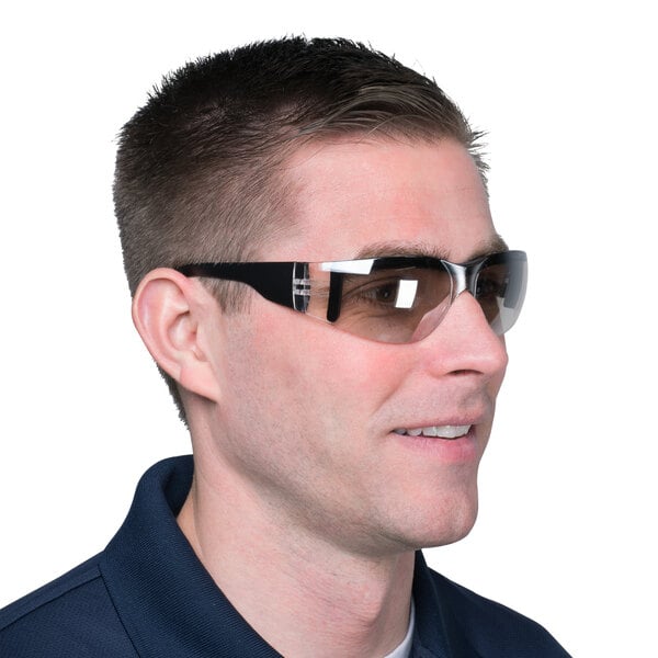 A man wearing Cordova scratch resistant safety glasses with black frames and indoor/outdoor lenses smiling.