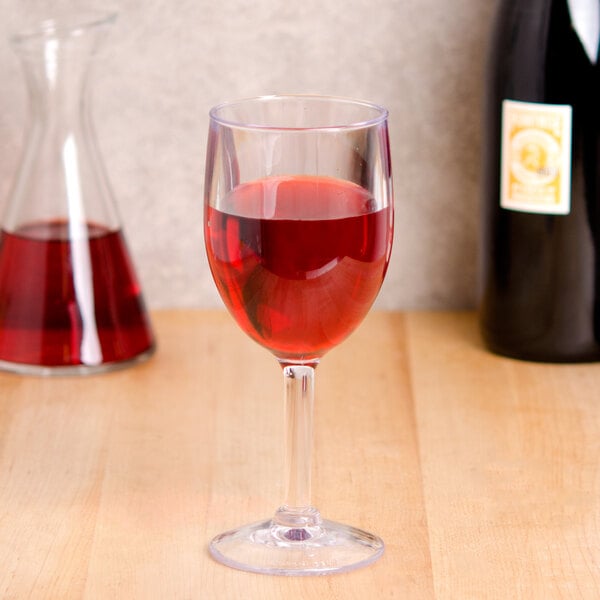 A GET SAN plastic wine glass filled with red liquid on a table in a winery cellar.