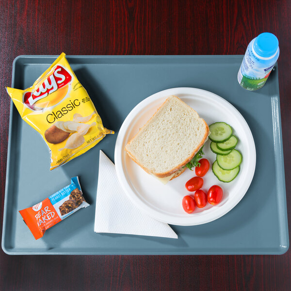 A teal Cambro dietary tray with a sandwich, vegetables, and a bottle of water.