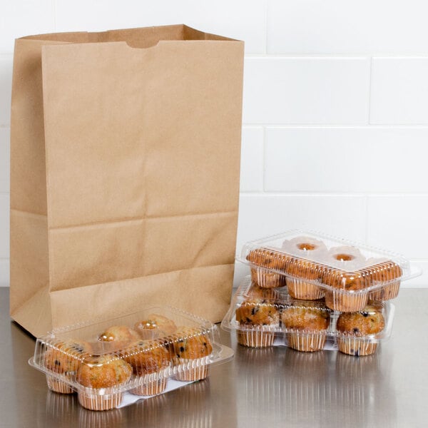 A brown paper barrel sack sitting next to a tray of muffins.