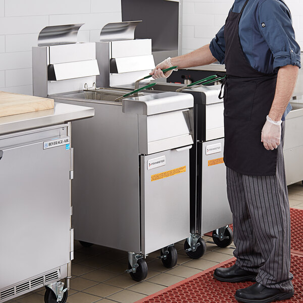A man using a Frymaster liquid propane floor fryer in a commercial kitchen.