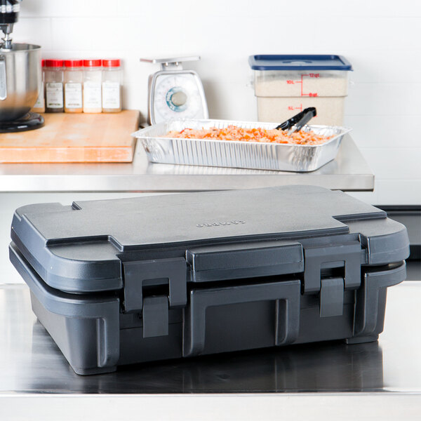A black plastic case with a lid on top holding food pans on a counter.
