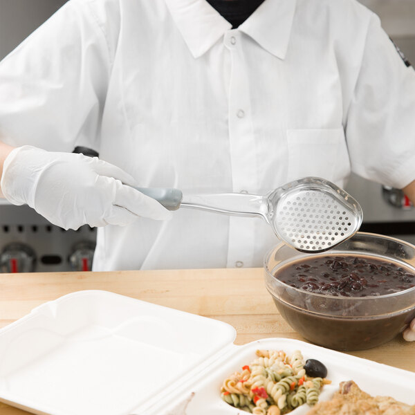 A person in a white coat using a Vollrath gray perforated oval spoodle to serve pasta.