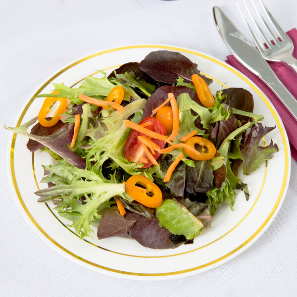A Fineline Silver Splendor plastic plate with a salad, fork, and knife on it.