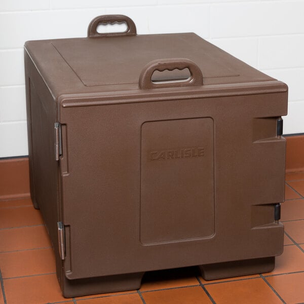 A brown plastic Carlisle Cateraide sheet pan carrier with a handle on a tile floor.