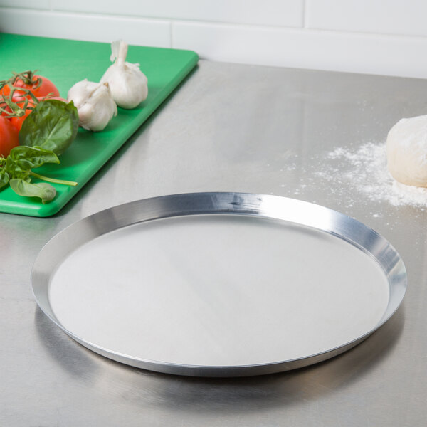 An American Metalcraft aluminum pizza pan on a white counter.