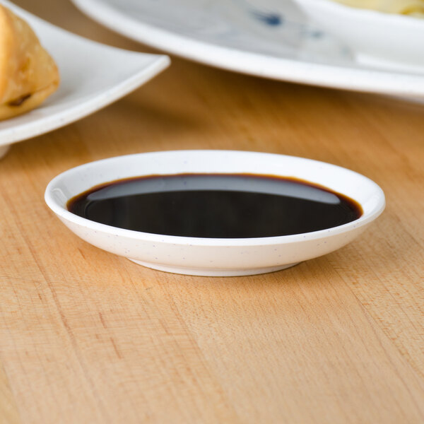 A blue Thunder Group Blue Bamboo sauce dish filled with sauce on a table.