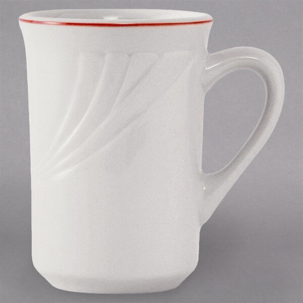 A white Tuxton China mug with a red curved design on the rim.