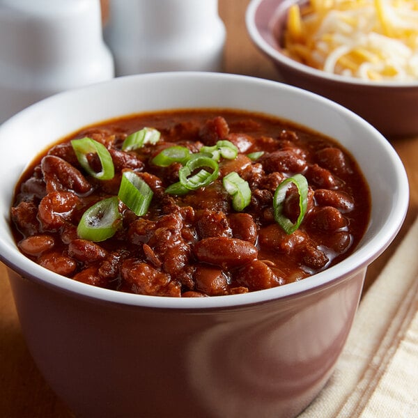 A bowl of Vanee chili with beans topped with cheese and green onions.