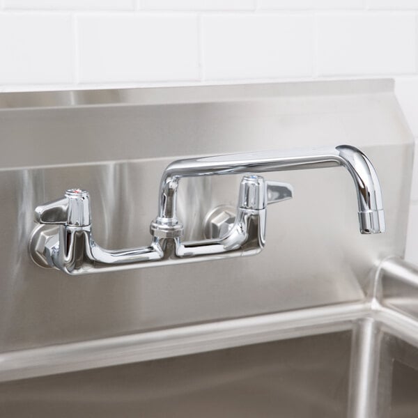 A close-up of an Equip by T&S wall mounted faucet with lever handles and a swing spout above a sink.