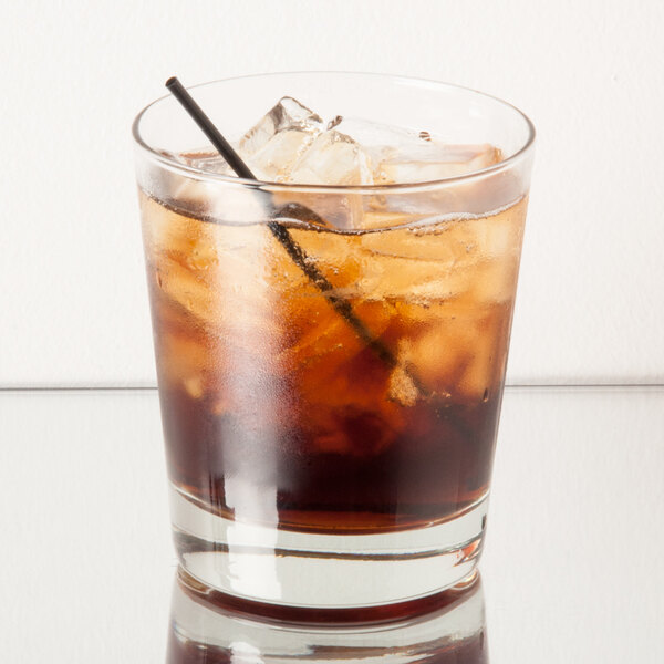 A Libbey English highball glass filled with a brown drink, ice, and a straw.