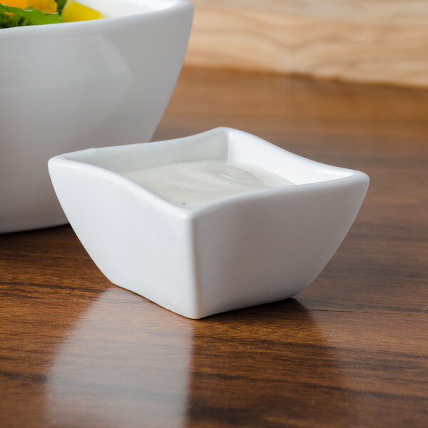A white American Metalcraft Squavy porcelain condiment cup filled with white sauce on a white background.