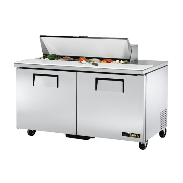 A True refrigerated sandwich prep table with food on top.