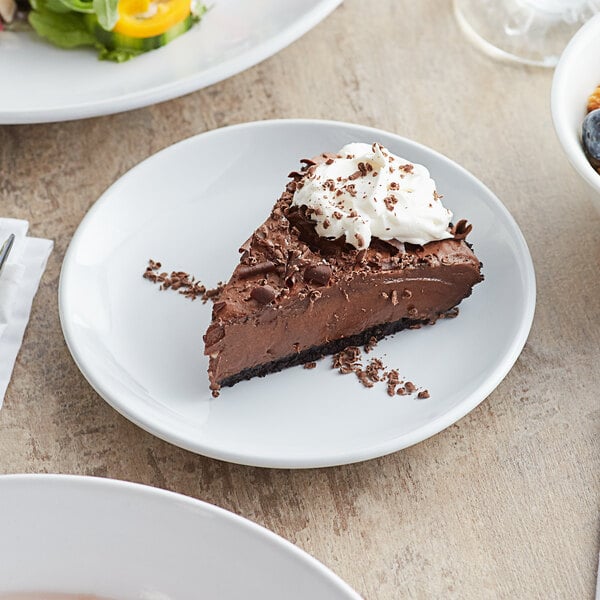 A slice of chocolate pie with whipped cream on top on a white Acopa stoneware plate.