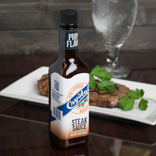 A Crystal Original Steak Sauce bottle on a white plate.