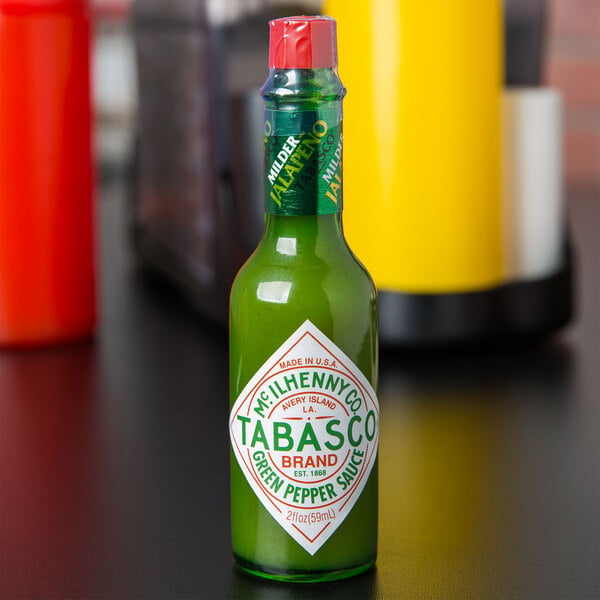 A close up of a green TABASCO® bottle with a white label. The bottle is filled with green liquid.