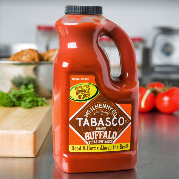 A 64 oz. bottle of TABASCO® Buffalo Style Hot Sauce on a counter.