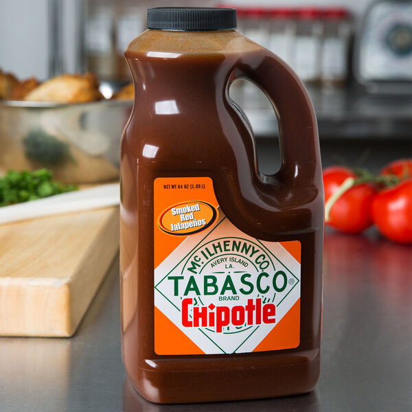 A 64 oz. jug of TABASCO Chipotle Pepper Hot Sauce on a counter with a label.