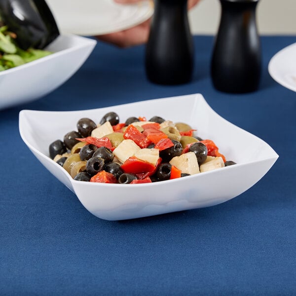 A close up of a white Fineline plastic serving bowl filled with salad, olives, and black olives.
