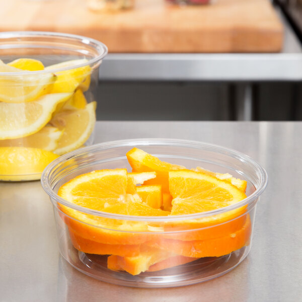 A clear Fabri-Kal deli container filled with sliced oranges and lemons.
