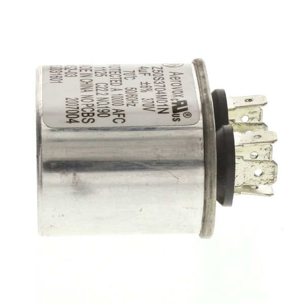 A close-up of a Giles capacitor, a small round metal cylinder with a black cover.