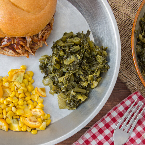 A plate of food with a pulled pork sandwich, corn, and green beans on a table.