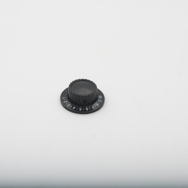 A black plastic thermostat knob with white numbers and a clear lens on a white background.