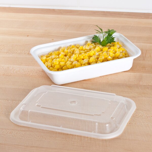 A white Pactiv rectangular plastic container of corn with a lid on a table.