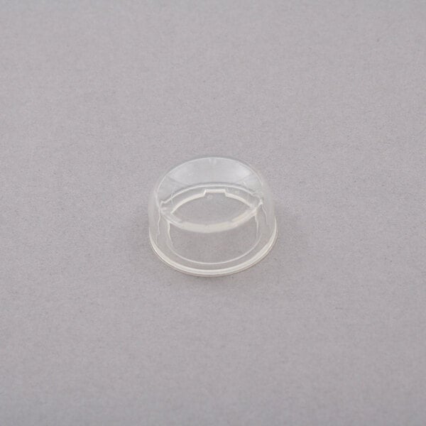 A clear plastic cap with a hole over a gray surface.