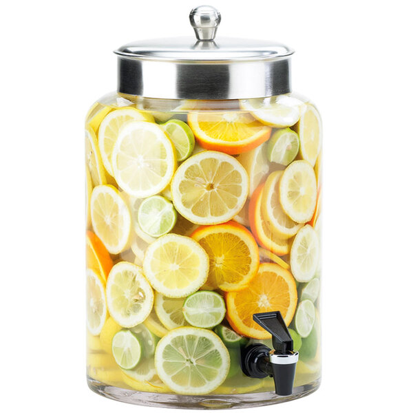 A Cal-Mil glass beverage dispenser with fruit slices inside.