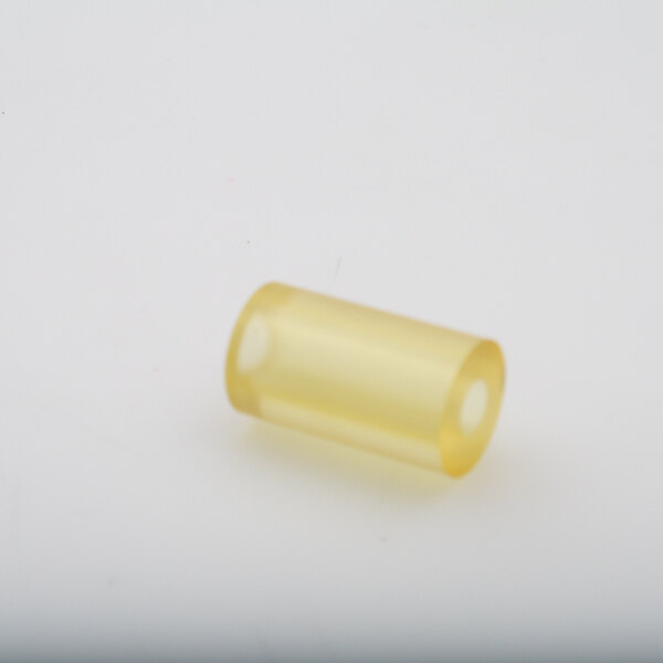 A yellow plastic tube with a hole on a white surface.