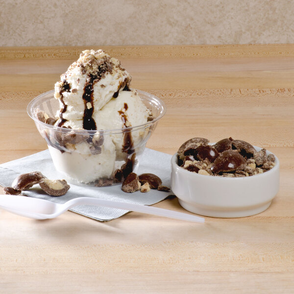 A WNA Comet Classic Sundae Cup filled with ice cream, chocolate syrup, and nuts with a spoon.