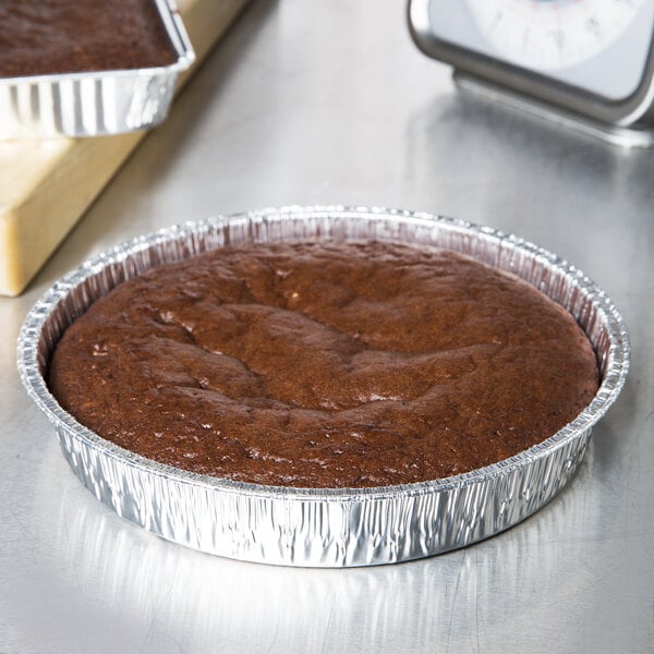 A brown chocolate cake in a 9" foil cake pan.
