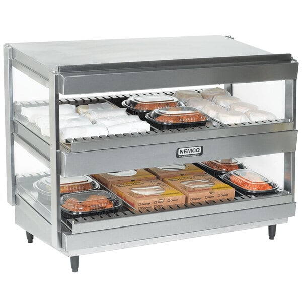 A stainless steel Nemco countertop food warmer with double shelves holding food trays.