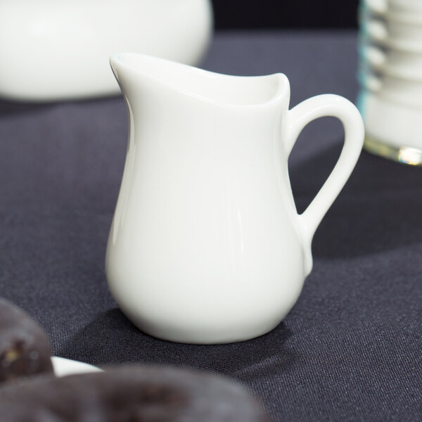 A white American Metalcraft porcelain bell creamer on a table.