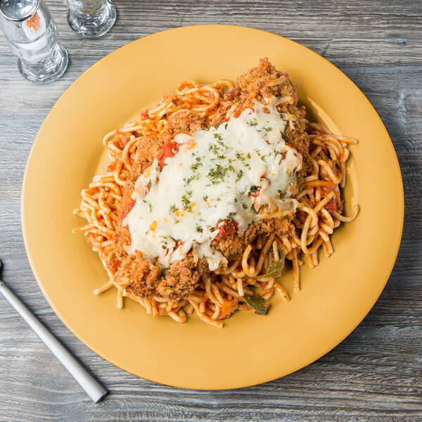 A GET Tropical Yellow melamine plate with spaghetti, meat, and cheese on top.