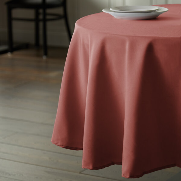 A round table with a mauve Intedge tablecloth and a plate on it.