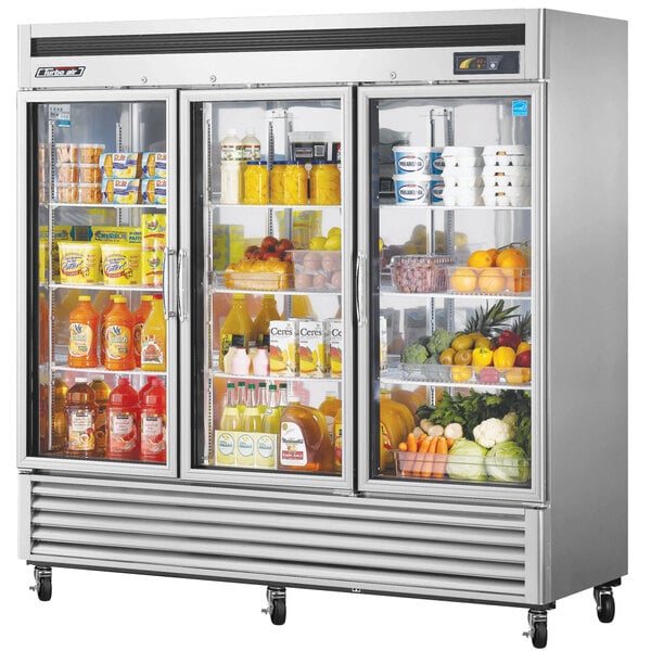A Turbo Air glass door reach-in refrigerator in a school kitchen filled with food.
