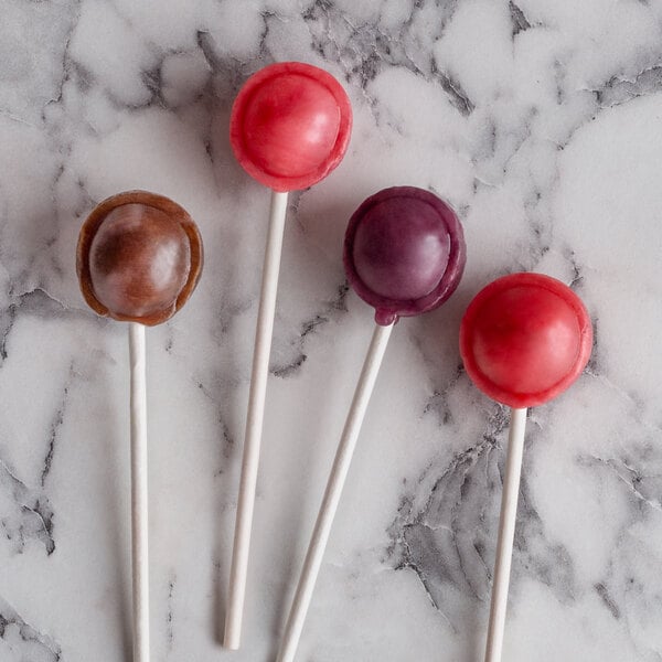 A group of round purple, red, and white lollipop sticks on a marble surface.