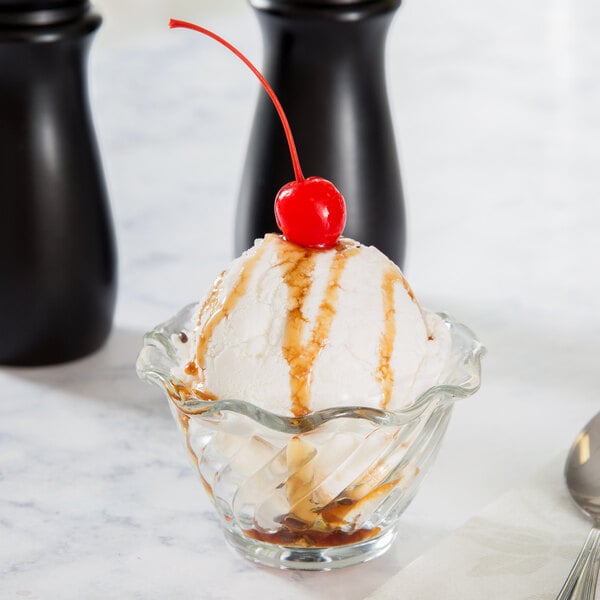 An Anchor Hocking Waverly sherbet glass with ice cream and a cherry on top.