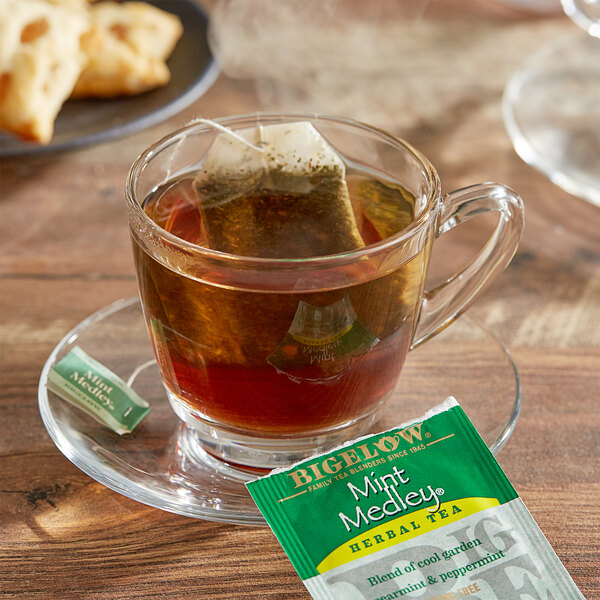A glass cup of Bigelow Mint Medley tea with a tea bag in it.