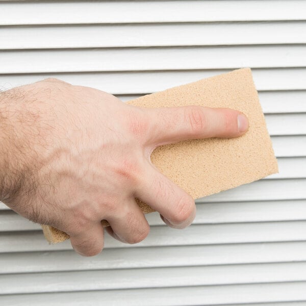 A hand cleaning a window with a Unger SootMaster sponge.