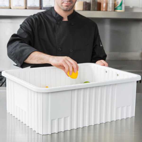 A man wearing a black coat putting a lemon in a white Metro Divider Tote Box.