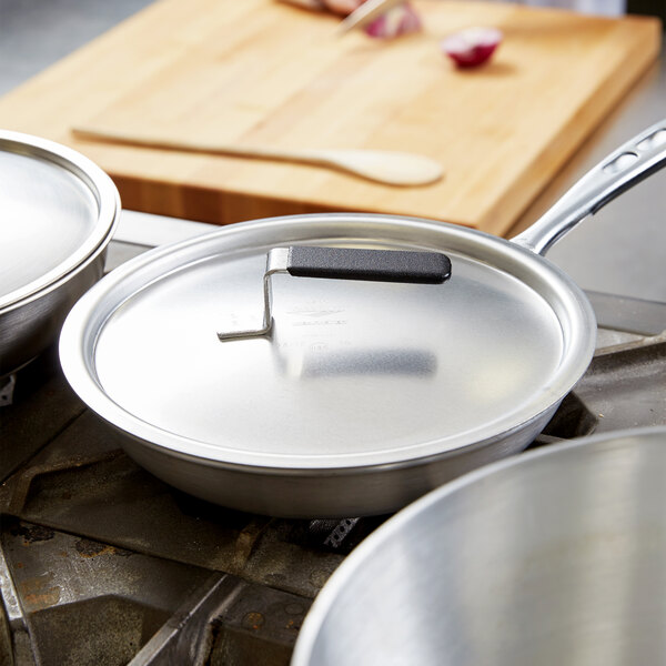 A Vollrath Wear-Ever domed aluminum pot cover on a pan on a stove.