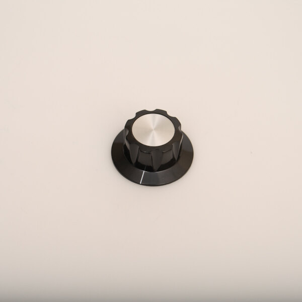 A close up of a circular silver knob with black edges.